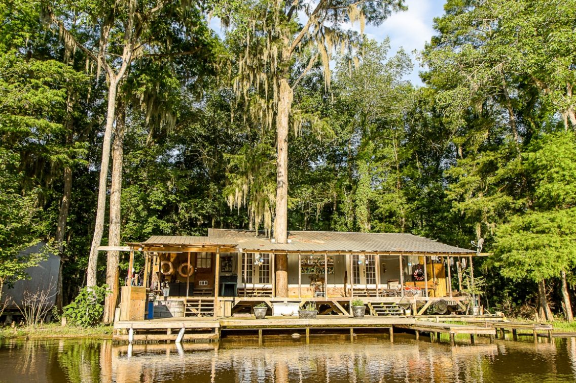 A house with a wooden dock sitting on the edge of the Louisiana swamp.