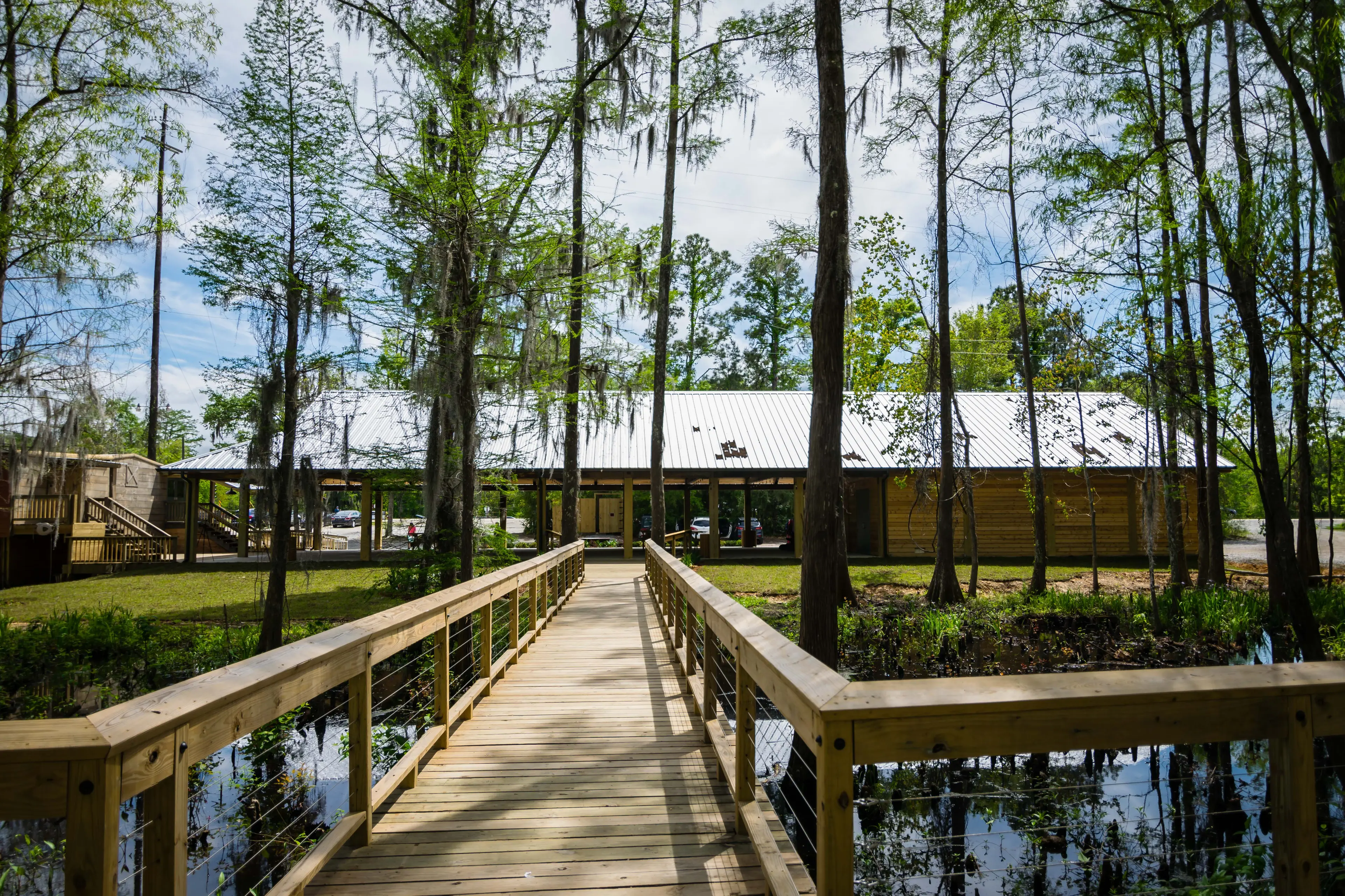 A long wooden bridge extending over swamp lands to reach a large wooden pavilion.